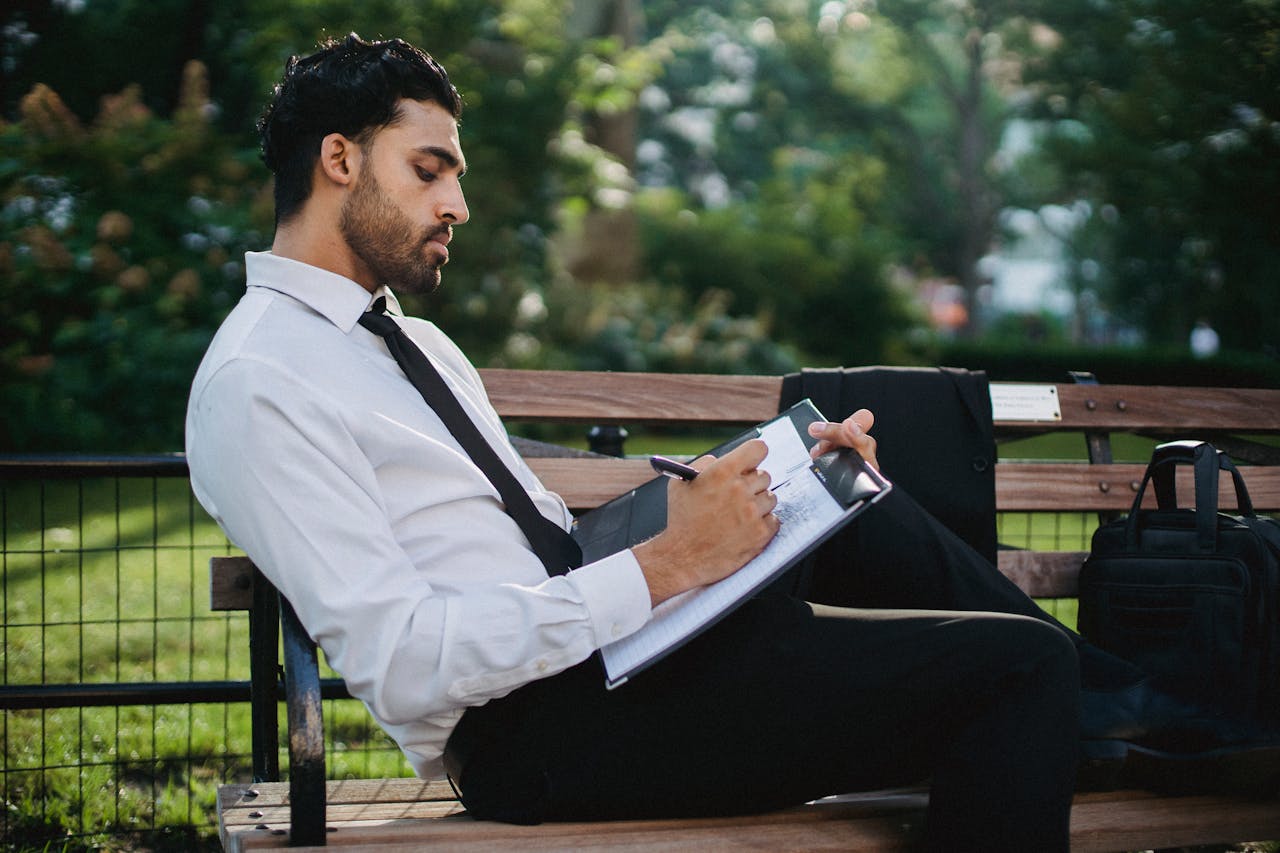 Professional writing on a clipboard outdoors, representing career transition and job search